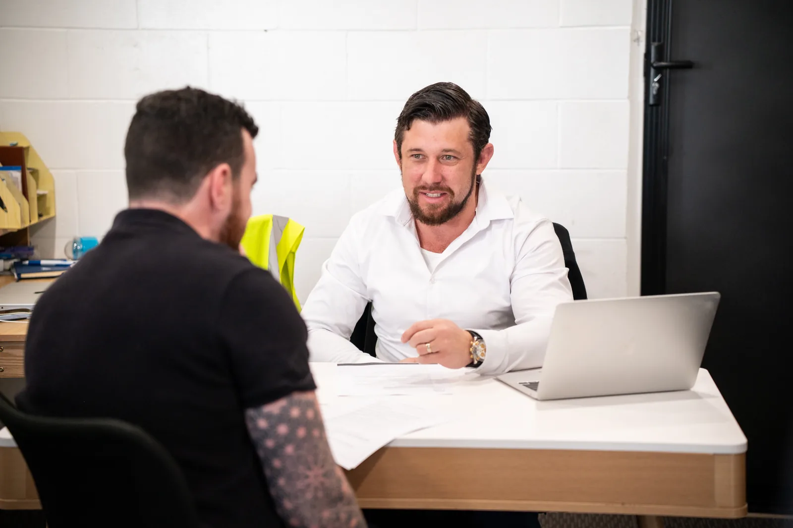 Two people talking across a meeting table