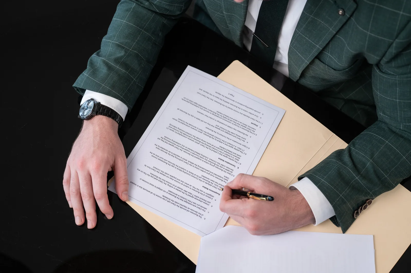 Hands and pen over a legal document in a manila folder