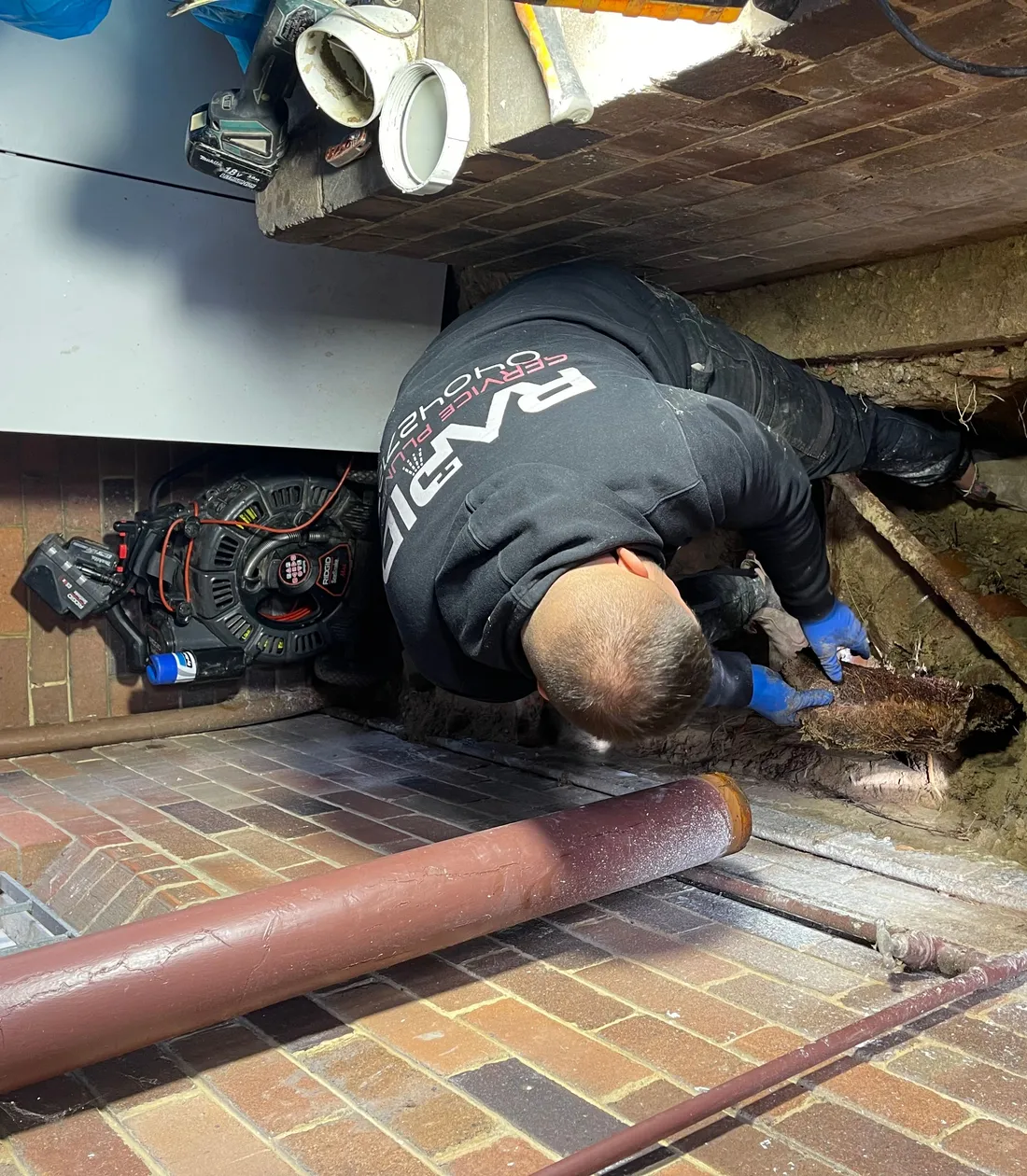 Rapid Service Plumbing plumber clearing a blocked drain under a house