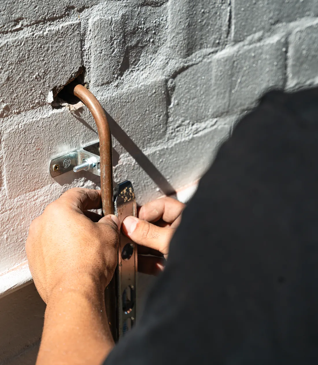 A Rapid Service Plumbing plumber fitting new copper pipe to a brick wall