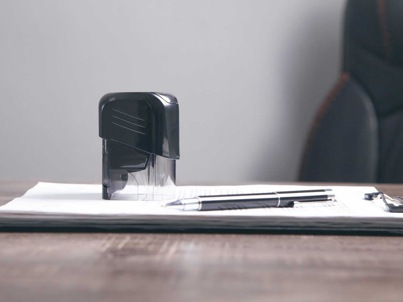 Self-inking rubber stamp resting on a clipboard of papers