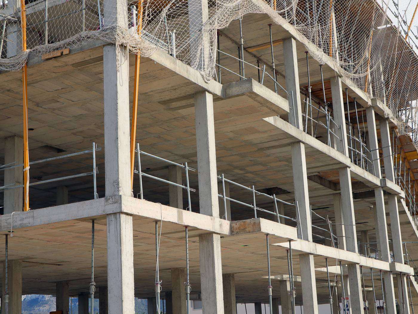 Multi-storey concrete frame with several trades' scaffolding in place