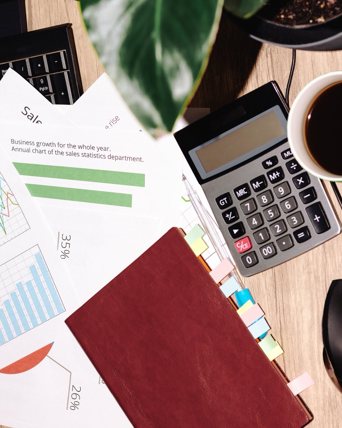 Accounting desk with printed ledgers, a calculator and a monitor showing a spreadsheet
