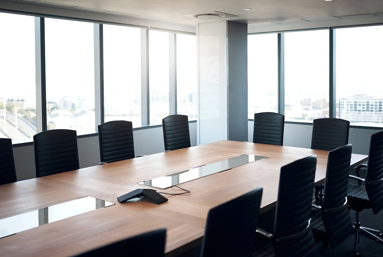 Empty boardroom lit from a window, chairs pushed in