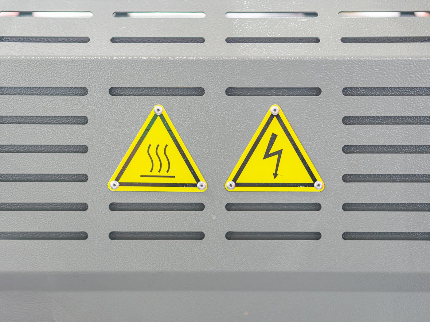 Hot surface and high voltage warning labels riveted to a ventilated grey enclosure