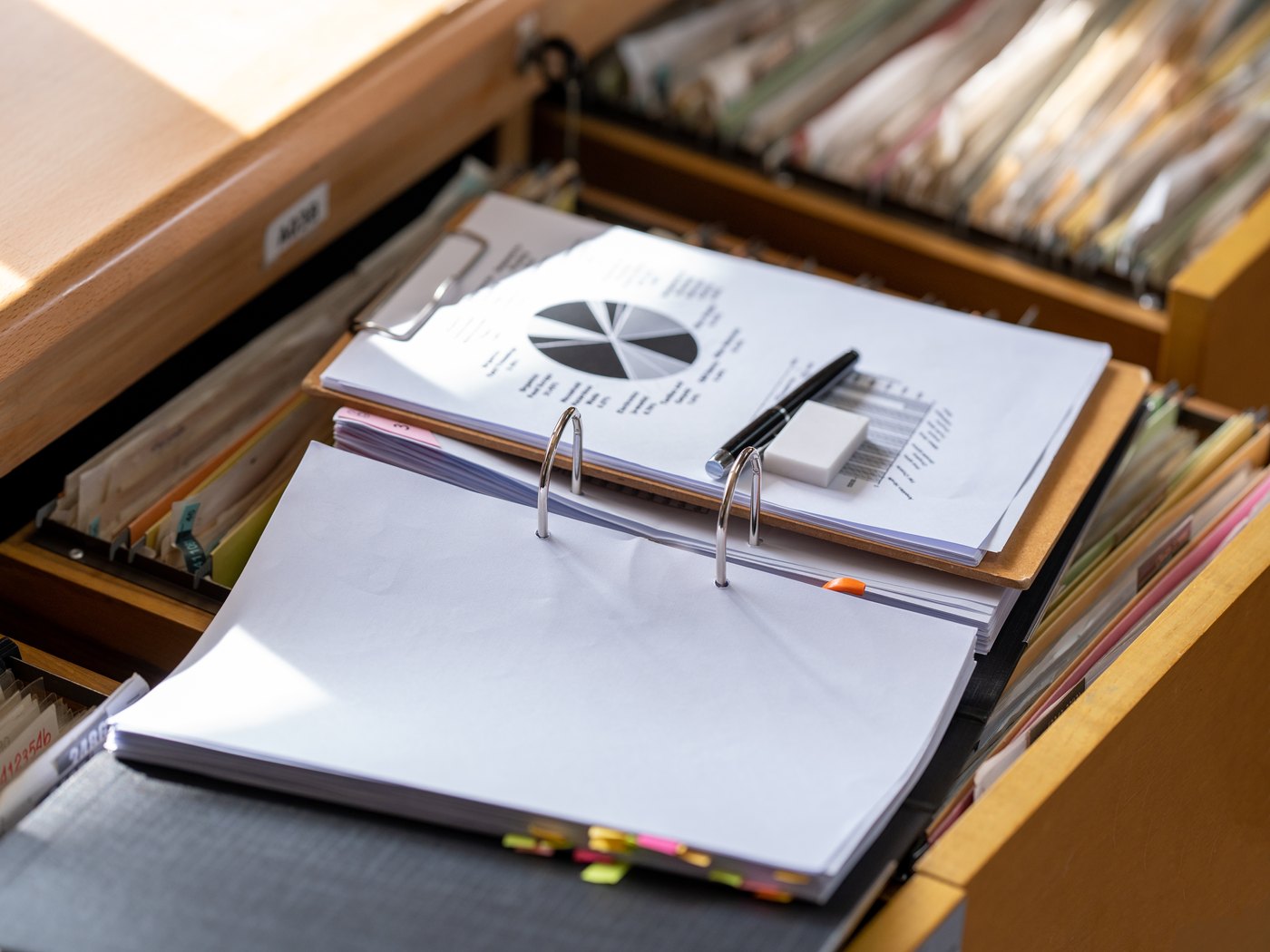Open filing cabinet drawer with a ring binder of service records resting on the files