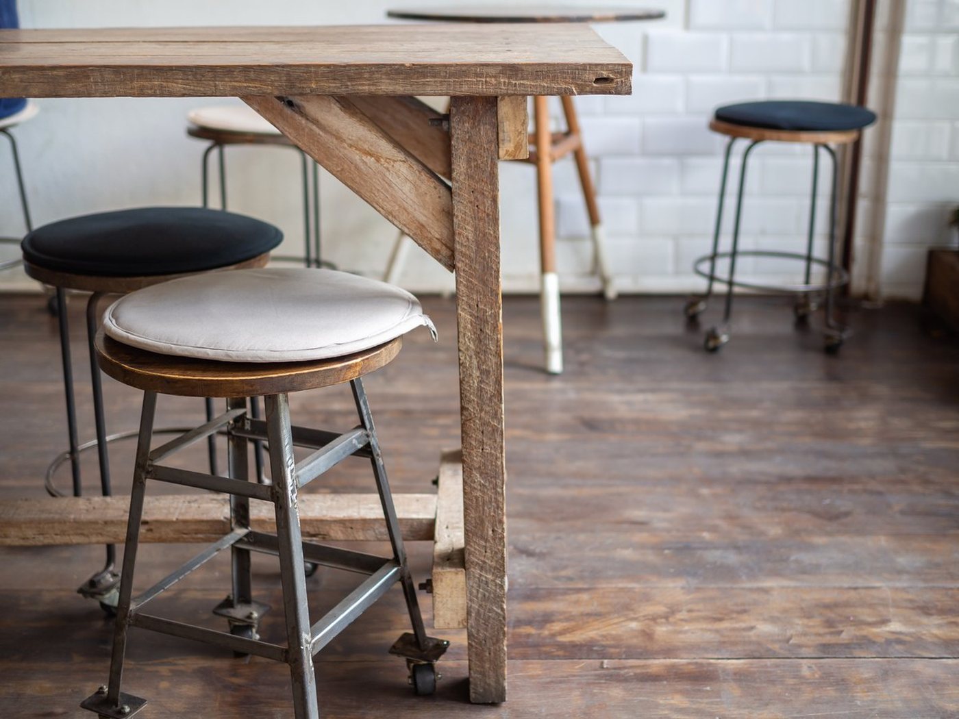 Empty bar with a timber high table and stools against a tiled wall