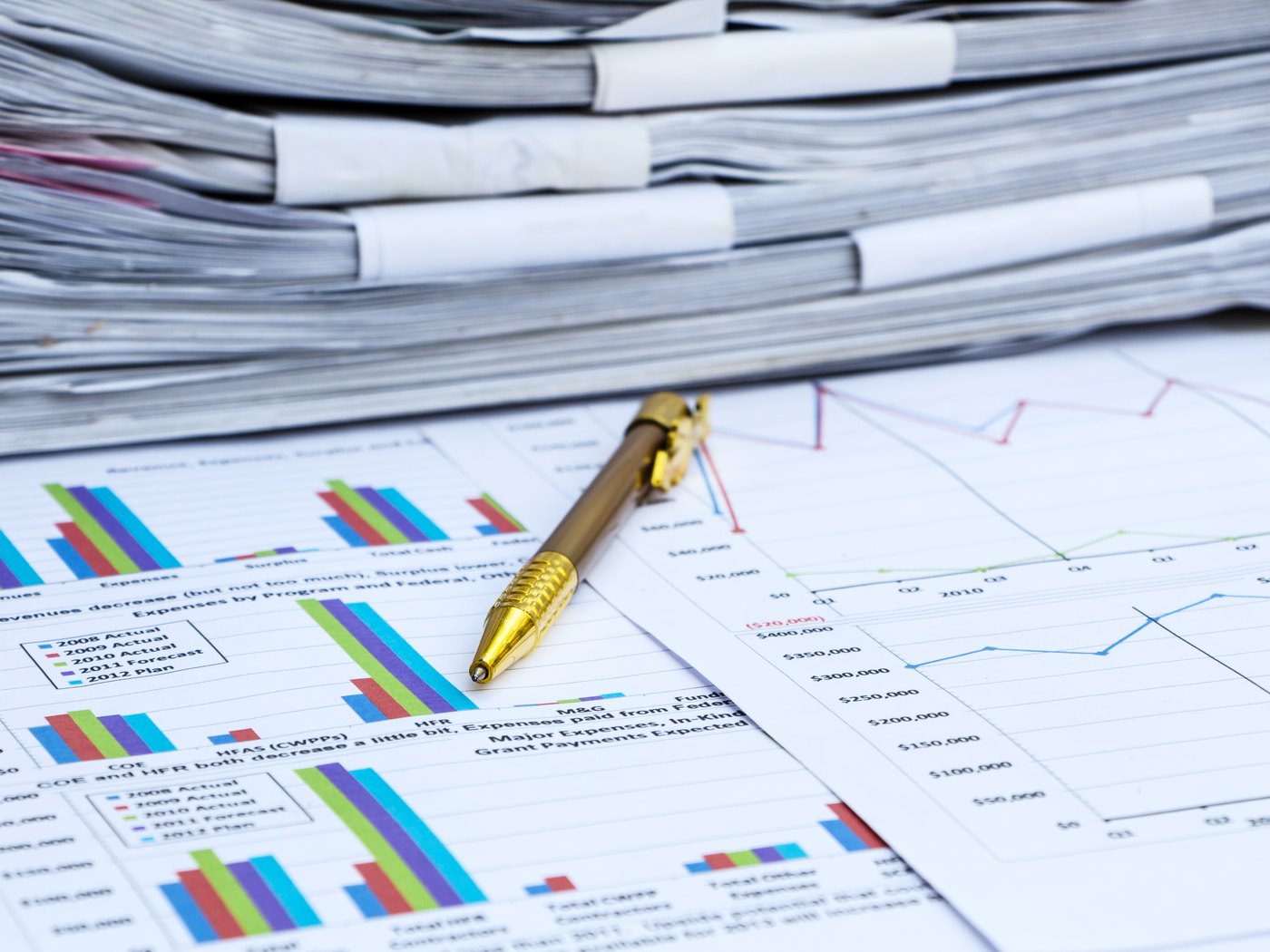 Stack of reports and a pen resting on printed charts