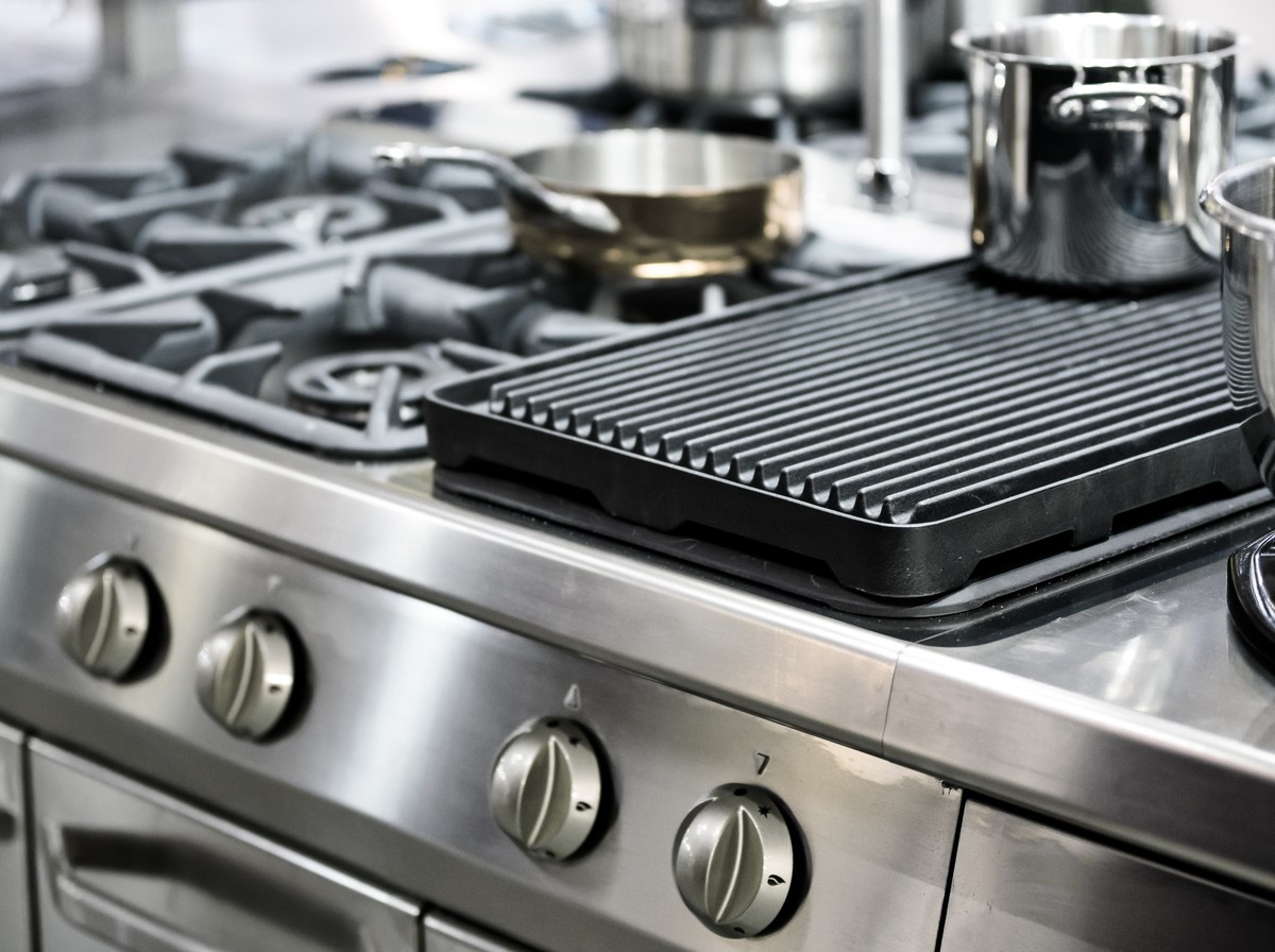 Unattended commercial gas range with a cast iron grill plate