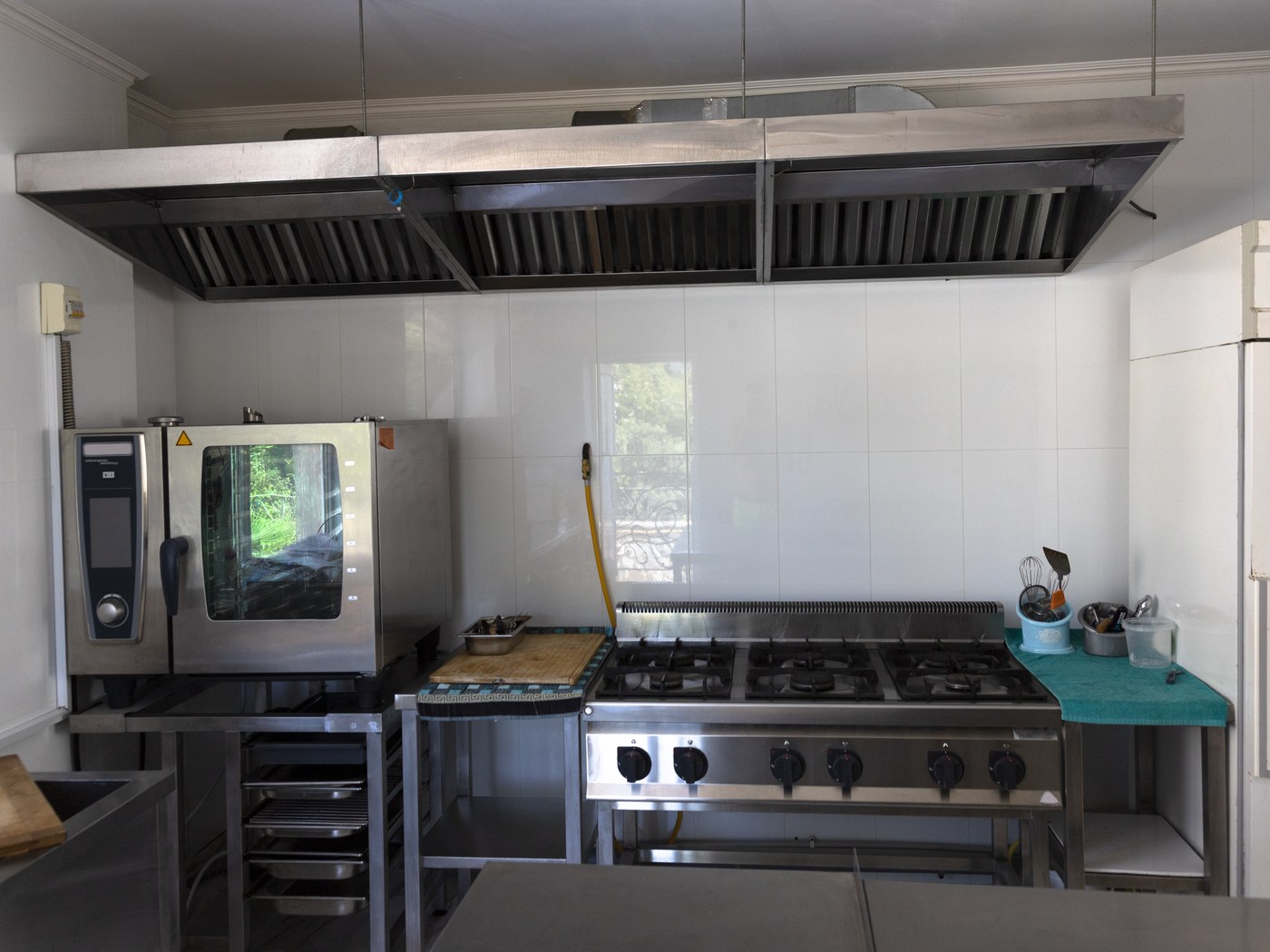 Stainless extraction canopy with baffle filters above an empty commercial range